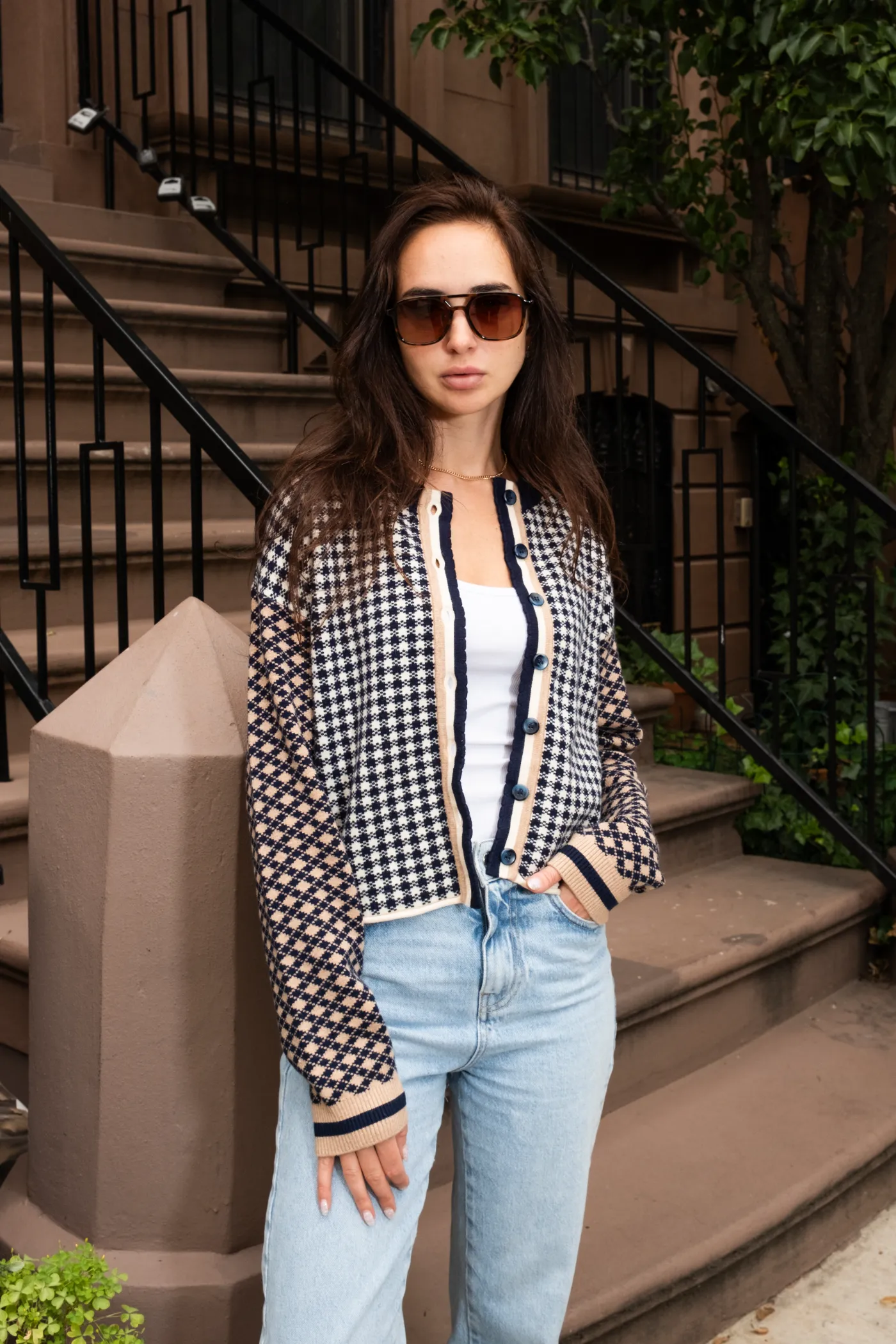 A model in a Central Park West patterned cardigan and jeans on a brownstone stoop