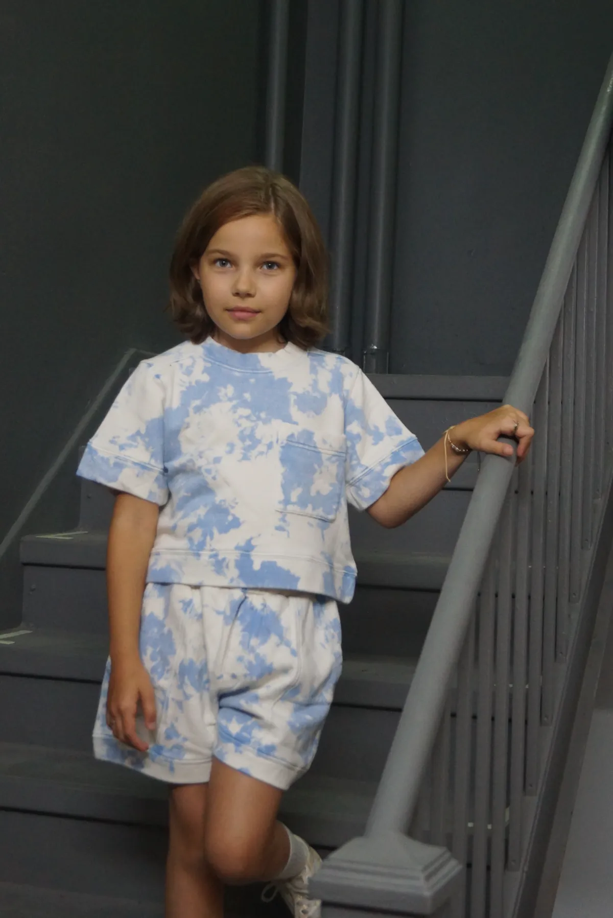 A child in a CPW Kids tie-dye set on a stoop